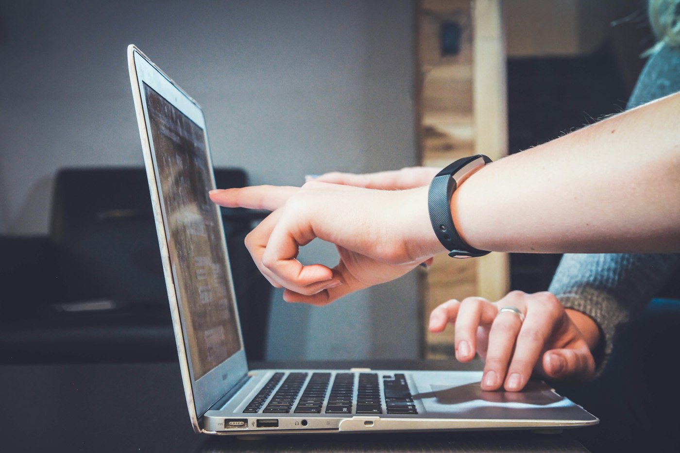 A person pointing at a laptop screen while checking the content